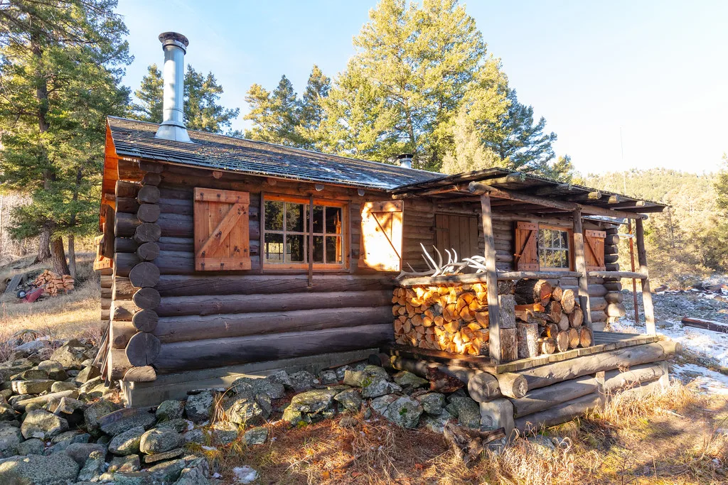 Log cabin with a stacked firewood porch in morning light