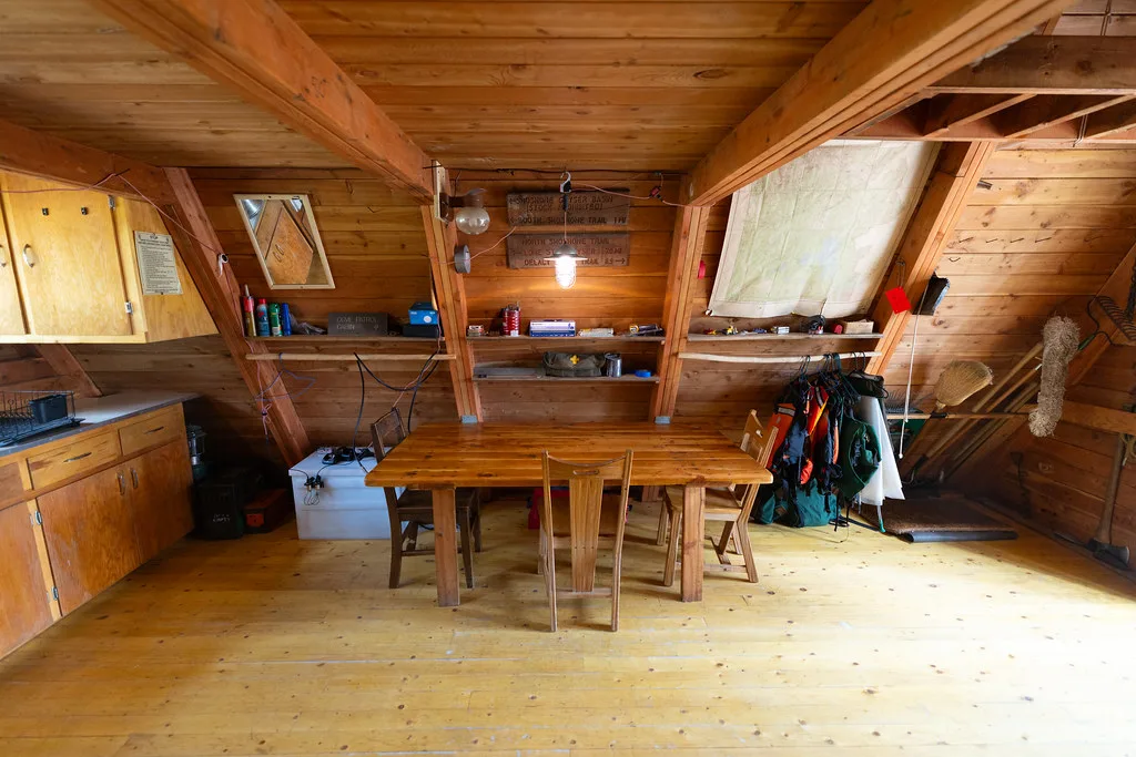 Dining table and chairs beneath the sloped cedar ceiling