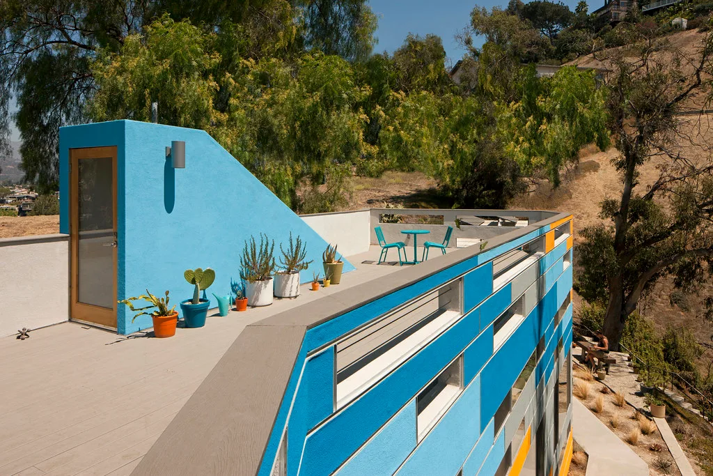 Roof deck with potted succulents and a blue stair tower above the hills