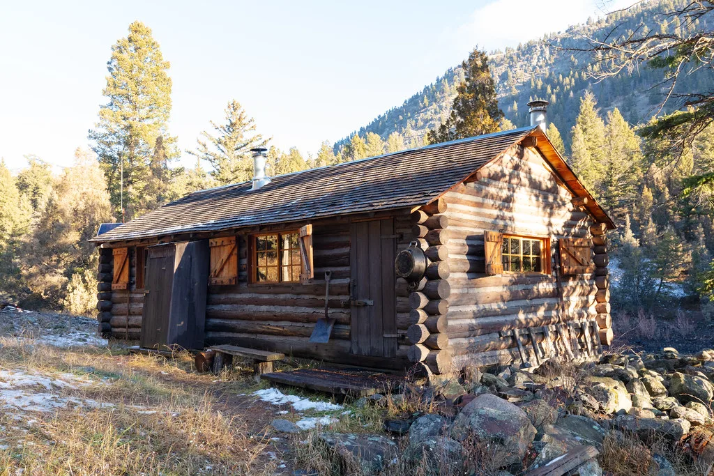 Log cabin among trees with light snow on the ground