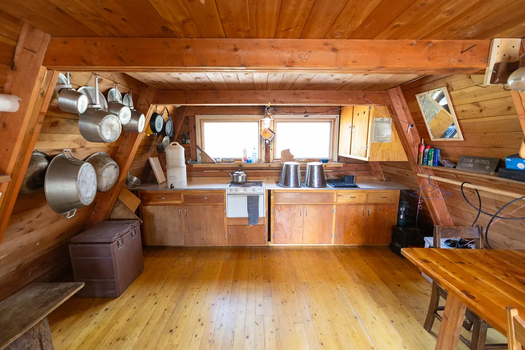 Kitchen wall of cedar cabinets, a window and hanging pots