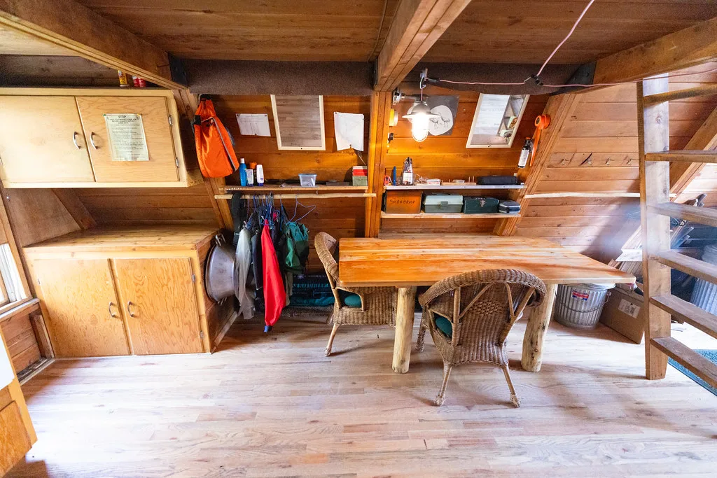 Slab dining table with wicker chairs under the sloping cedar walls