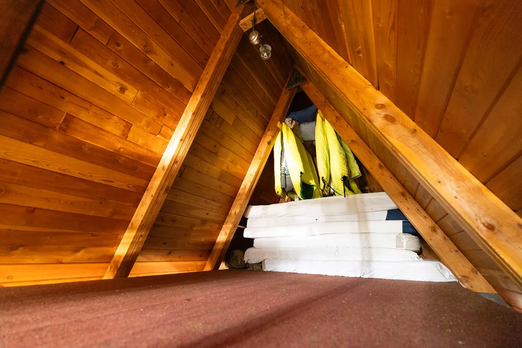 Sleeping loft tucked under the peak of the A-frame with stacked mattresses