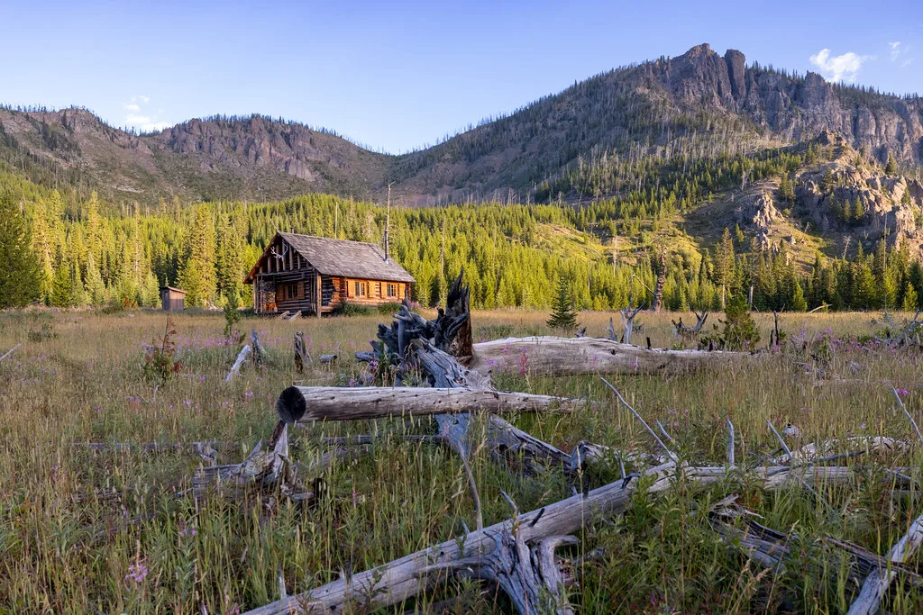 Cabin in a marshy mountain valley with rugged peaks behind