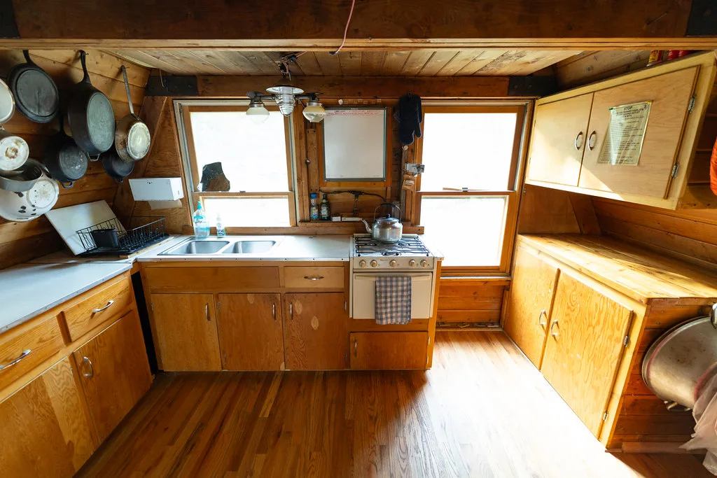 Wood-cabinet kitchen with a double sink, gas range and pots hung on the wall
