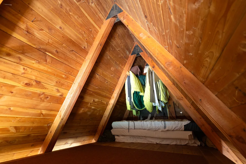 Peaked sleeping loft with rolled bedding under the A-frame ridge