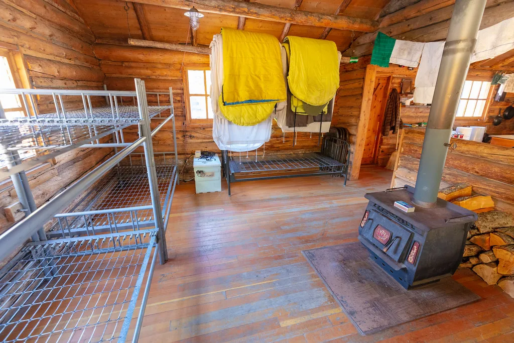Back room with metal bunks, a wood stove and blankets drying on a line